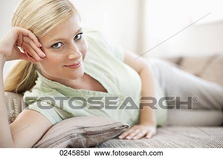 Stock Image - portrait of young woman relaxing on sofa. Fotosearch