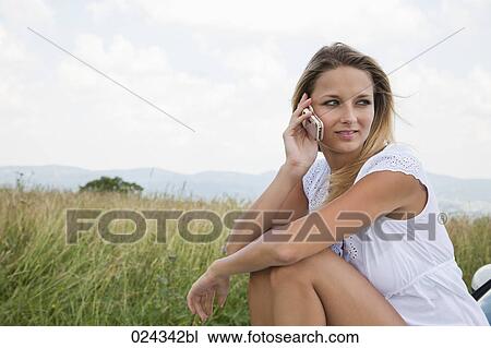 portrait of young woman siiting on bonnet of car talking on mobile phone View Large Photo Image Stock Image - portrait of young woman siiting on bonnet of car talking on mobile phone. Fotosearch