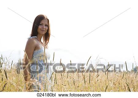 Stock Image - portrait of young woman standing in field. Fotosearch