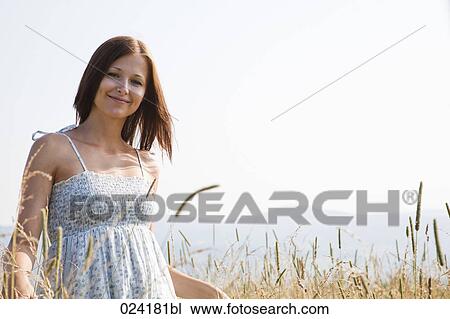 Stock Image - portrait of young woman standing in field. Fotosearch