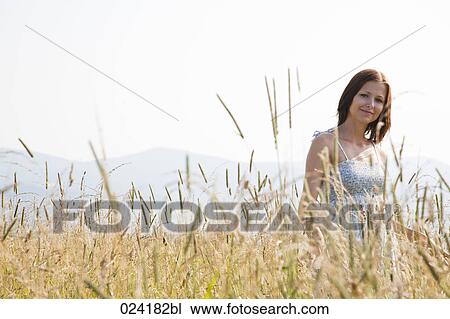 Stock Image - portrait of young woman standing in field. Fotosearch