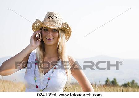 portrait of young woman standing in field talking on mobile phone View Large Photo Image Stock Image - portrait of young woman standing in field talking on mobile phone. Fotosearch