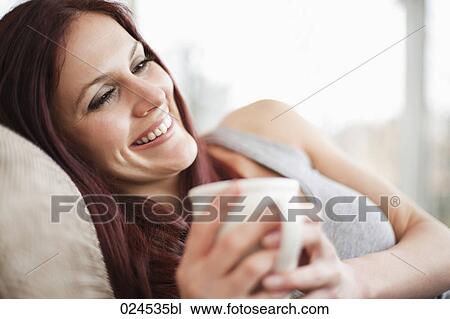 portrait of young woman with coffee cup relaxing on sofa View Large Photo Image Stock Image - portrait of young woman with coffee cup relaxing on sofa. Fotosearch