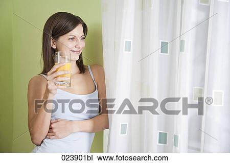 Stock Image - portrait of young woman with glass of juice. Fotosearch
