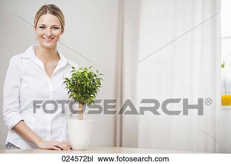 Stock Image - portrait of young woman with potted plant. Fotosearch