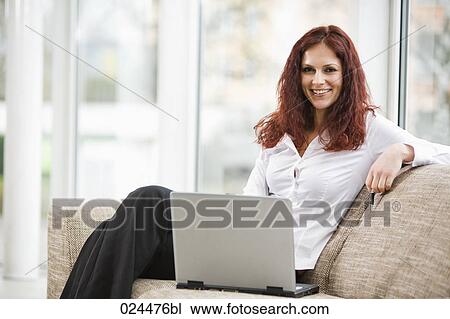 Stock Image - portrait of young woman working with laptop computer at home. Fotosearch