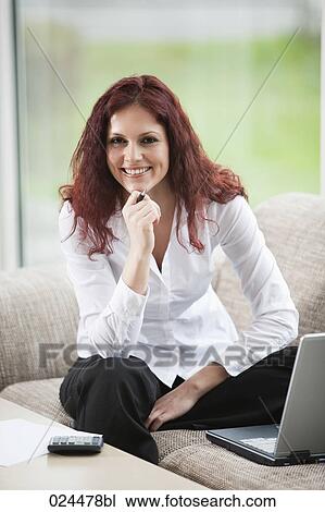 Stock Image - portrait of young woman working with laptop computer at home. Fotosearch