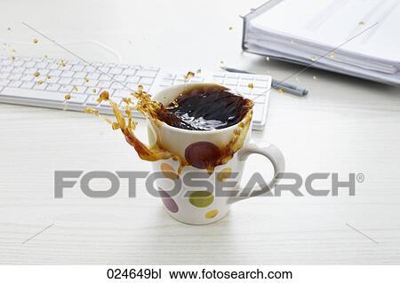Stock Image - still life of coffee spilling out of cup on desk. Fotosearch