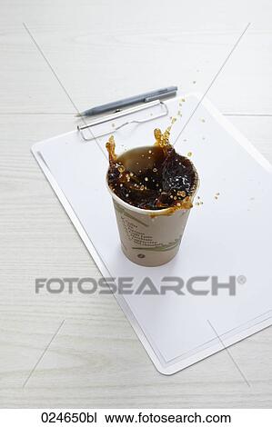 Stock Image - still life of coffee spilling out of paper cup on desk. Fotosearch