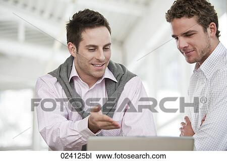 Stock Image - two businessmen having discussion in front of computer. Fotosearch