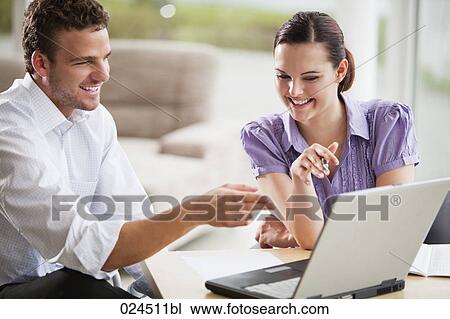 Stock Image - two people talking in front of laptop computer. Fotosearch
