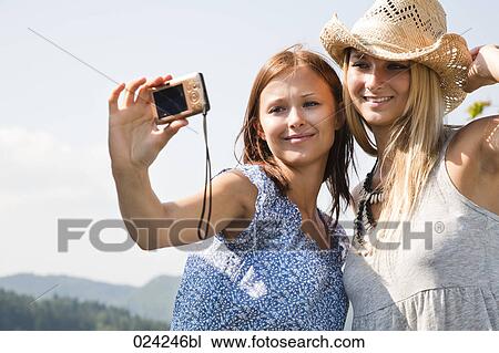 Stock Image - two women taking self-portrait with digital camera. Fotosearch