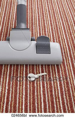 Stock Image - vacuum cleaner accidentally vacuuming key on carpet. Fotosearch