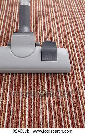 Stock Image - vacuum cleaner accidentally vacuuming ring on carpet. Fotosearch