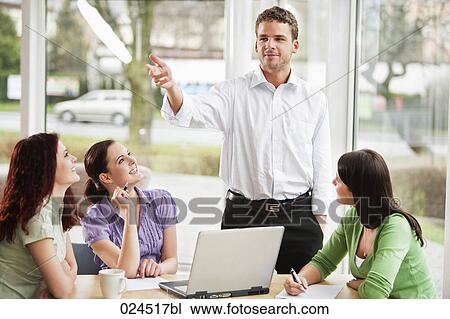 Stock Image - young businessman giving presentation to female colleagues. Fotosearch