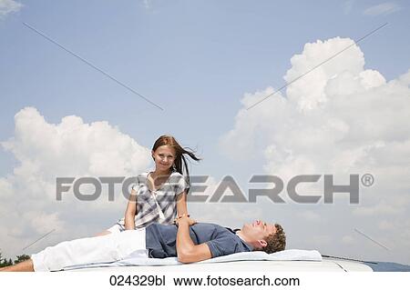 young couple lying on roof of car View Large Photo Image Stock Image - young couple lying on roof of car. Fotosearch