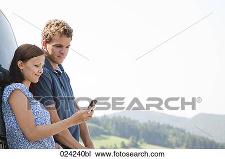 Stock Image - young couple reading message on mobile phone. Fotosearch