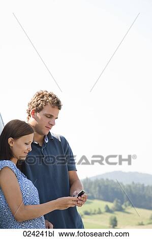 young couple reading message on mobile phone View Large Photo Image Stock Image - young couple reading message on mobile phone. Fotosearch