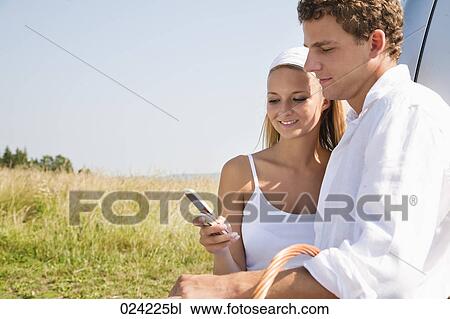 young couple reading text message on mobile phone together View Large Photo Image Stock Image - young couple reading text message on mobile phone together. Fotosearch