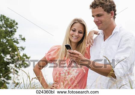 Stock Image - young couple reading text message on mobile phone. Fotosearch