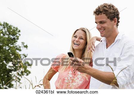 Stock Image - young couple reading text message on mobile phone. Fotosearch