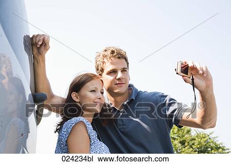 Stock Image - young couple taking picture of themselves with digital camera. Fotosearch