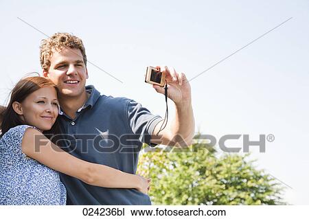 Stock Image - young couple taking picture of themselves with digital camera. Fotosearch