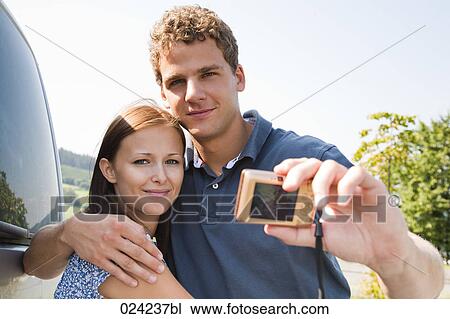 Stock Image - young couple taking picture of themselves with digital camera. Fotosearch