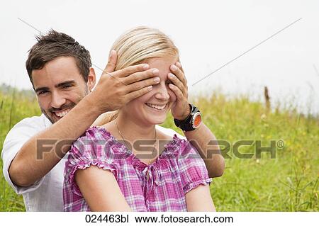 Stock Image - young man playing peekaboo with girlfriend. Fotosearch