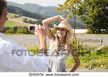 Stock Image - young man taking portrait of girlfriend with digital camera. Fotosearch