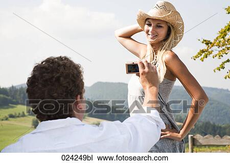 Stock Image - young man taking portrait of girlfriend with digital camera. Fotosearch