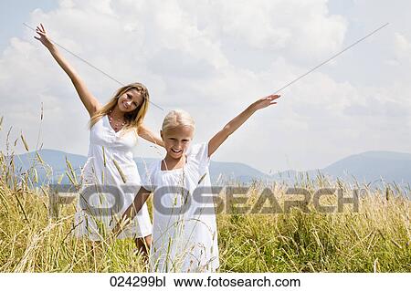 young woman and daughter walking through meadow View Large Photo Image Stock Image - young woman and daughter walking through meadow. Fotosearch