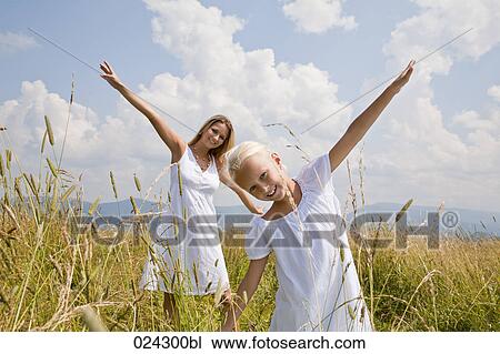 Stock Image - young woman and daughter walking through meadow. Fotosearch