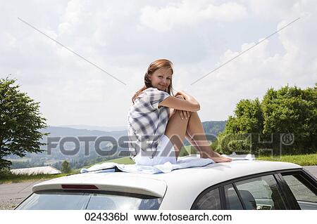 young woman sitting on roof of car View Large Photo Image Stock Image - young woman sitting on roof of car. Fotosearch