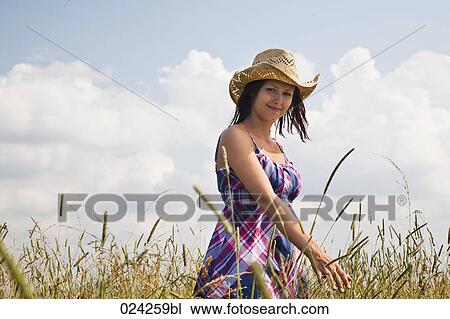 Stock Image - young woman standing in field. Fotosearch