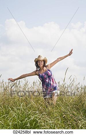Stock Image - young woman walking through field. Fotosearch