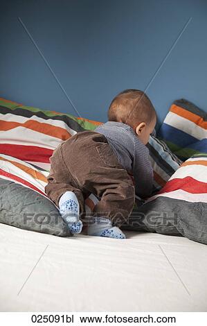 Stock Image - baby crawling through bed. Fotosearch