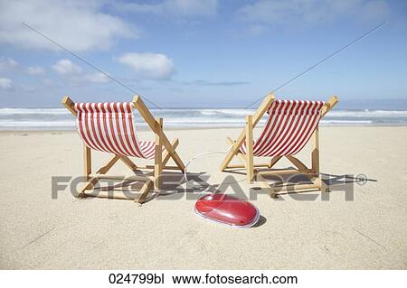 Stock Image - computer mouse and sun loungers on sandy beach. Fotosearch