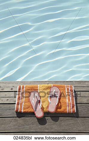 Stock Image - flip flops on towel at swimming pool. Fotosearch