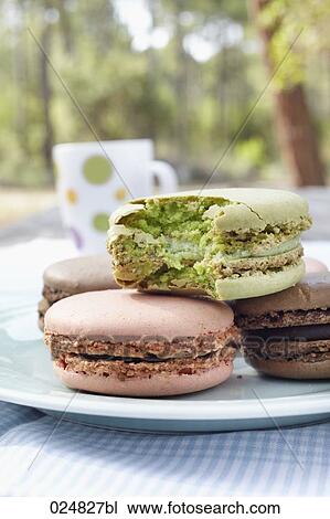 Stock Image - four macarons on plate one half eaten. Fotosearch
