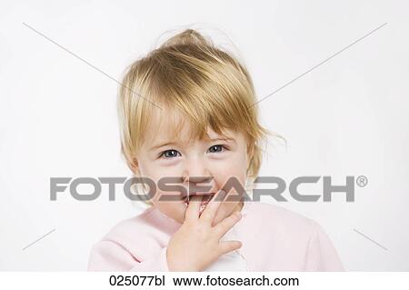 Stock Image - portrait of baby girl putting finger in mouth. Fotosearch