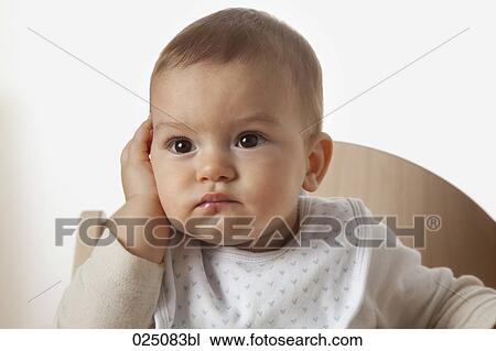 Stock Image - portrait of baby in high chair looking astonished. Fotosearch