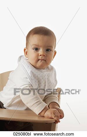 Stock Image - portrait of baby sitting in high chair. Fotosearch
