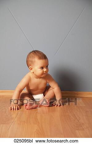 Stock Image - portrait of baby wearing nappy sitting on floor. Fotosearch