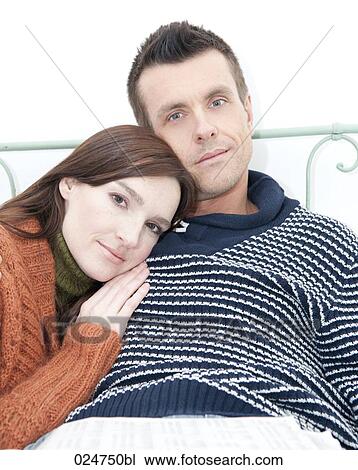 Stock Image - portrait of young couple lying in bed together. Fotosearch