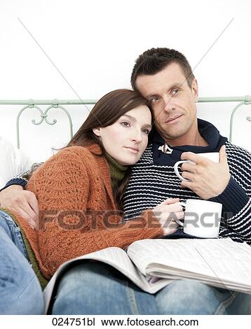 portrait of young couple lying in bed together holding mugs View Large Photo Image Stock Image - portrait of young couple lying in bed together holding mugs. Fotosearch