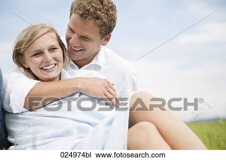 Stock Image - portrait of young couple sitting in grass. Fotosearch