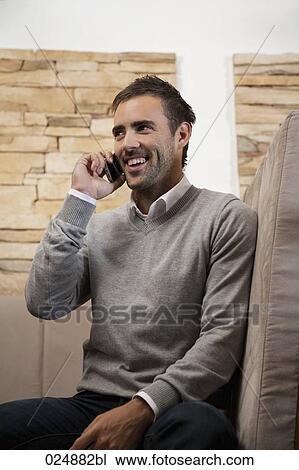 Stock Image - portrait of young man at restaurant talking on mobile phone. Fotosearch