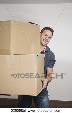 Stock Image - portrait of young man carrying moving boxes. Fotosearch