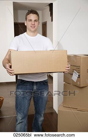 Stock Image - portrait of young man carrying moving box. Fotosearch